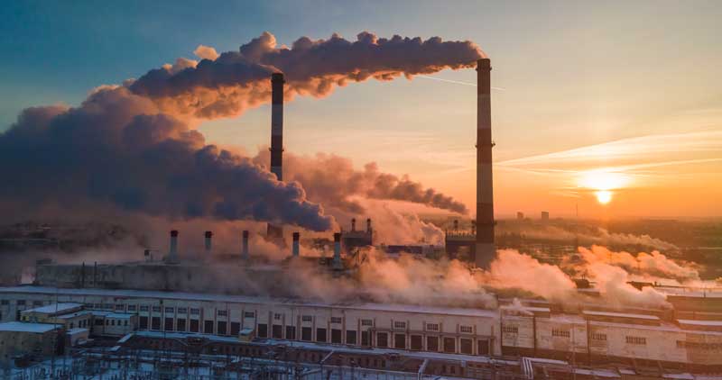 Smoke stacks over sunrise sky background